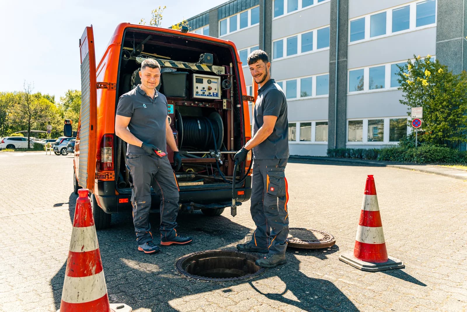 Zwei Mitarbeiter der Kaseo GmbH am Spülfahrzeug neben dem offenen Kanalschacht