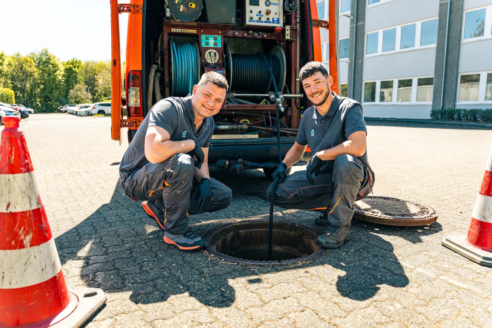 Zwei Mitarbeiter der Kaseo GmbH führen den Spülschlauch in den offenen Schacht