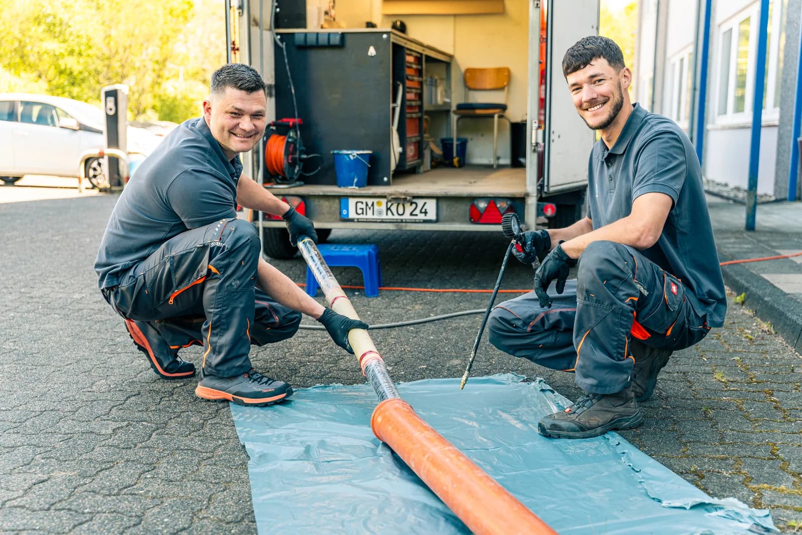 Vorbereitung eines Schlauchliners auf der Folie neben dem Werkstattanhänger